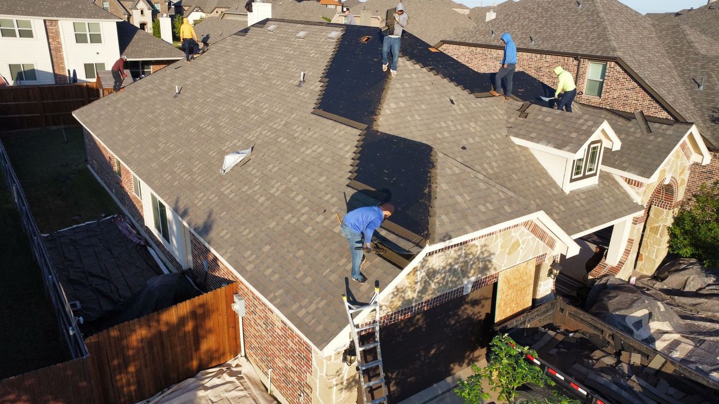 Roofing crew removing old shingles on a brick home in the Cleburne area