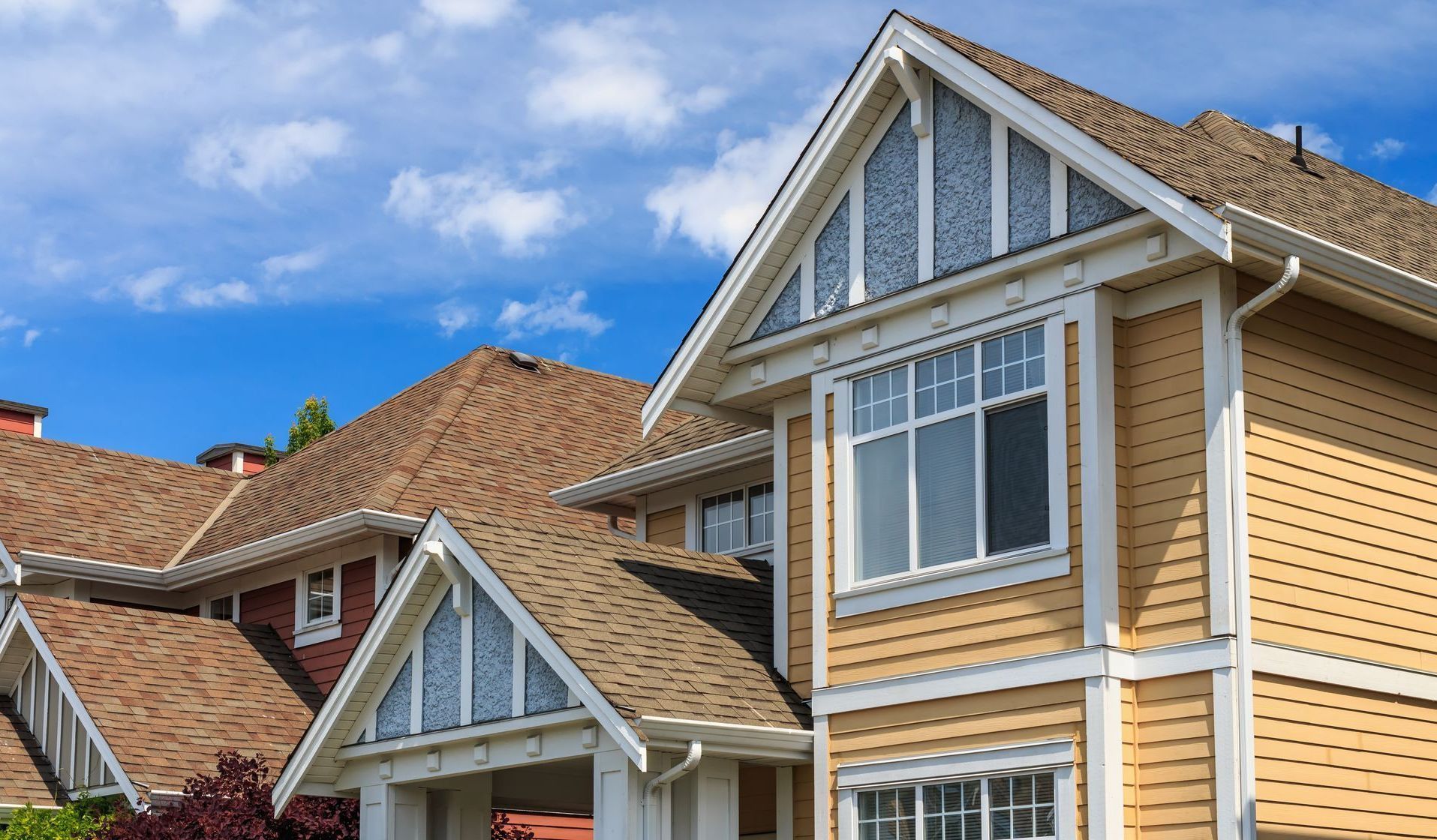 Homes with asphalt shingle roofs under a blue sky