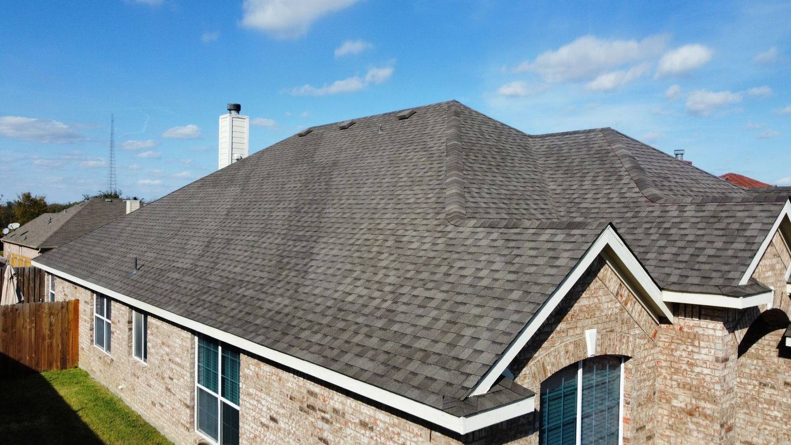 Completed gray asphalt shingle roof on a brick home